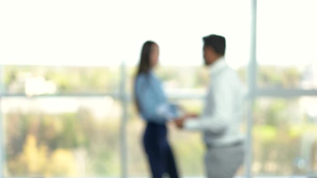 Blurred office life for keying. Meeting, handshaking and passing by. Co-workers glad to meet each other. Meeting in office at the morning.