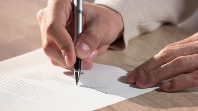 Filling up contract form. Man's hands signing contract using pen.