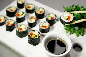 Vegan sushi rolls with quinoa, vegetables and soy-nut sauce on a white plate, light background. Vegan Healthy Food Concept.