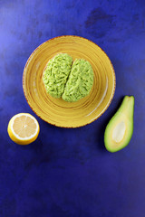 Avocado and lemon, pasting of sandwiches with avocado on a yellow plate on the ultraviolet background, green spread made with avocado, half a lemon, vegetarian food, pop art, Latin American cuisine