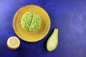 Avocado and lemon, pasting of sandwiches with avocado on a yellow plate on the ultraviolet background, green spread made with avocado, half a lemon, vegetarian food, pop art, Latin American cuisine
