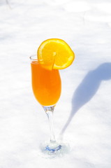 
Fouger is filled with orange juice with a slice of orange standing on the snow.