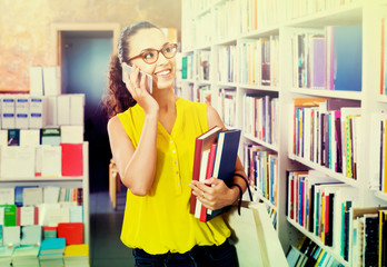 Smiling  woman chatting on mobile phone and taking  books