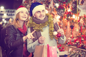 Girl with boy in Christmas hat choosing decorations