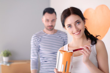 Portrait of happy smiling young couple painting interior wall of new house. young couple