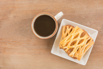top view of pineapple pie in a ceramic dish served with black coffee on old wooden background. breakfast concept.