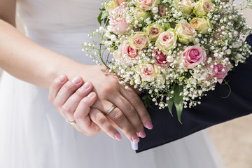 Groom in suit and bride in wedding dress holding hands