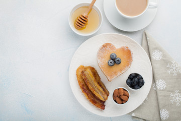 A stack of delicious pancakes with honey, coffee and blueberries on a light blue background. Great Breakfast for Valentine's day. Top view with copy space