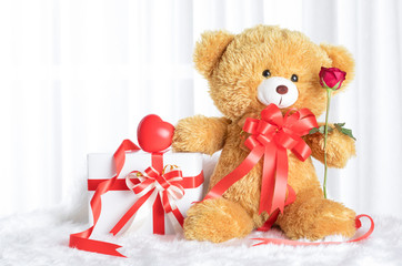 Bear doll is holding an amazing of red roses.