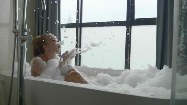Beautiful woman relaxing in bubble bath lying in bathtub. Beauty care, leisure activity and healthcare concept.
