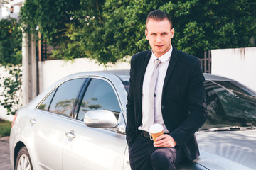 Handsome businessman  standing with coffee cup near the car