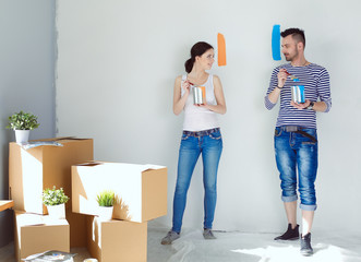 Portrait of happy smiling young couple painting interior wall of new house. young couple
