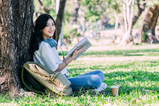 Students young woman relax and reading a book sitting on grass in park
