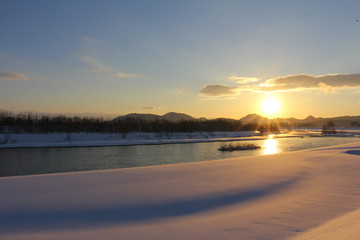 川と日没　冬　雪　太陽　青空　秋田県