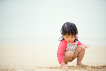 Little asian girl playing on beach.