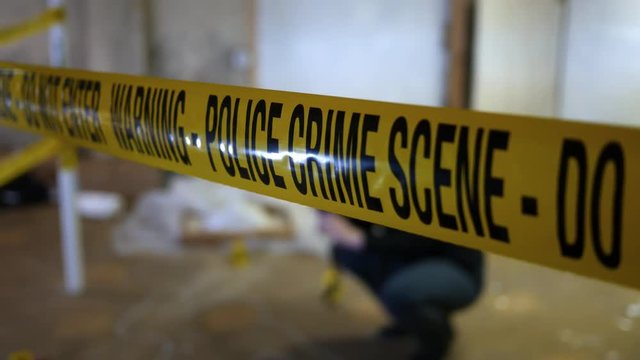 Forensic Crime Photographer at murder scene behind yellow police line - ALT