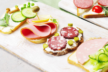 Sandwiches from a variety of ingredients on a light rustic surface. 