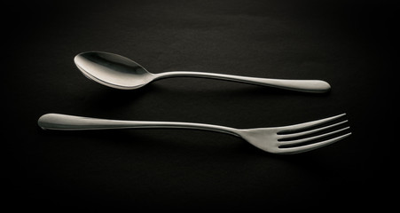 Stainless steel fork and spoon on dark background