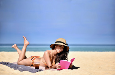 Girl vacation relaxing on the beach reading a book.