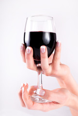 Woman hand with french nails manicure holding wine glass with red wine. Close up