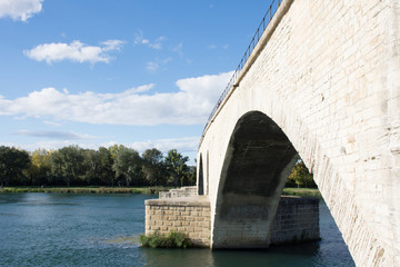 Saint Benezet Bridge in Avignon with an arch, the Rhone River and opposite riverbank in the image.