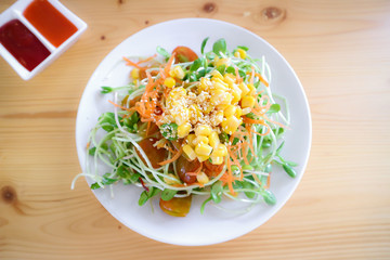 Sunflower sprout salad with carrots slide, corn sprinkled and white Sesame Seeds topped, eat with salad dressing on dish that is beneficial to the healthy.