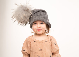 Portrait of happy little girl. Cute little girl in beige dress in a gray hat isolated on white background.