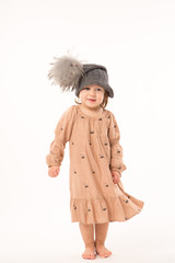Portrait of happy little girl. Cute little girl in beige dress in a gray hat isolated on white background.