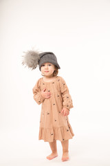 Portrait of happy little girl. Cute little girl in beige dress in a gray hat isolated on white background.