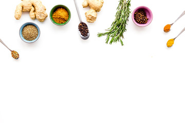 Colorful dry spices in bowls and spoons near ginger and rosemary on white background top view copy space
