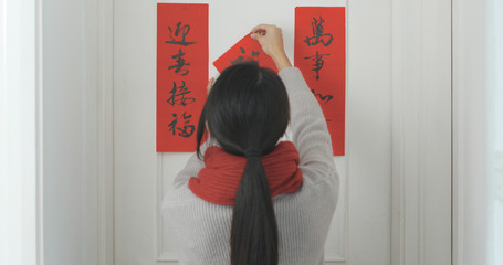 Woman sticking chinese calligraphy on the door