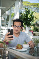 Fototapeta na wymiar Handsome man using mobile phone at the cafe