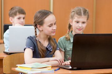 Happy kids at laptop in the classroom