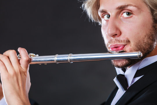 Elegantly dressed male musician playing flute