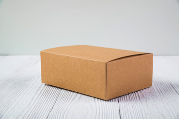 Empty Package brown cardboard box or tray on bright wooden table with copy space.