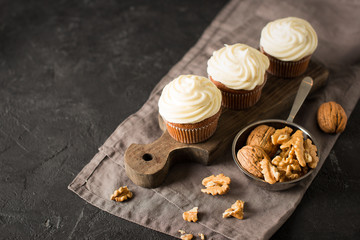 Carrot cupcakes or muffins with nuts on dark background