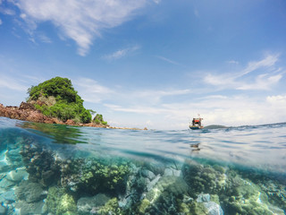 Fishing boat with small island in the sea over coral reef