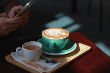 Man took picture with smartphone.Hot Coffee latte with tulip foam style.