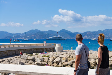 Couple walking along stone coast of Cannes, Côte d'azur