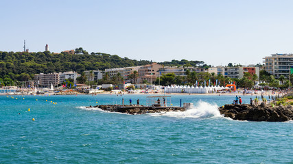 Obraz premium View of Beach of Juan-Les-Pins with waves at stone coast