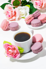 Fototapeta na wymiar macaroon cookies, cup of coffee and flowers on white table, top view