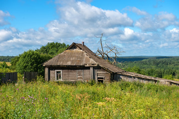 Old abandoned wooden house with green grass hills in the background