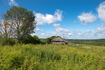 Old abandoned wooden house with green grass hills in the background