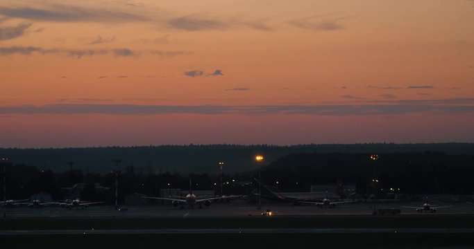 View to the airport with jets in the dusk and airplane taking off
