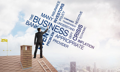 Young businessman standing on house roof and writing leadership skill concept. Mixed media