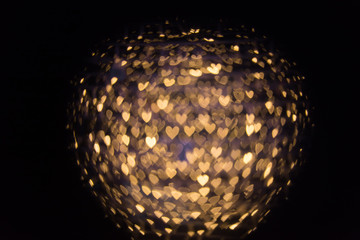 Blurred background with golden light bokeh in heart shape.