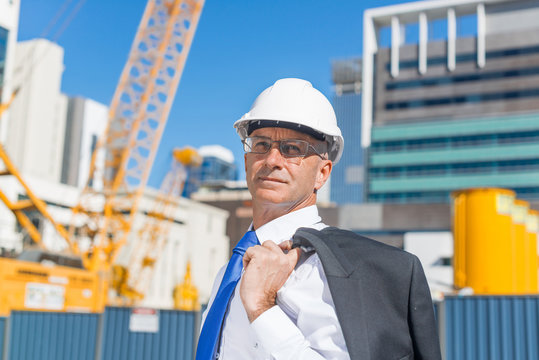 Senior elegant builder man in suit at construction site on sunny summer day
