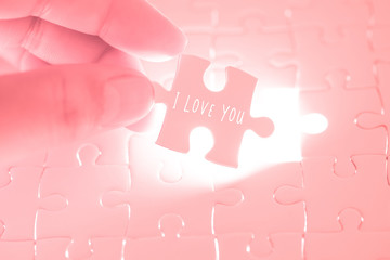 I love you word on pink jigsaw puzzle being holding by the hands of men. Valentines day concept...