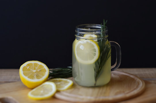 Horizontal photo of cold homemade lemonade with rosemary and lemon slices in a cocktail jar. Detox drink