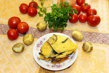 Hot ready moussaka is served on a porcelain plate among vegetables and spicy herbs. Fresh vegetables for cooking light dinner, Moussaka - a traditional Greek dish step by step cooking process